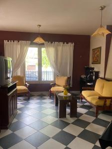 ein Wohnzimmer mit einem TV, Stühlen und einem Tisch in der Unterkunft Conti House in Capilla del Monte