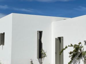a white building with black windows and a plant at Villa Serene Milos in Empourios