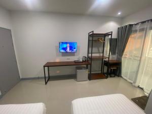 Habitación con escritorio y TV en la pared. en SUPATTRA PLACE ( สุพัตราเพลส ) en Pai