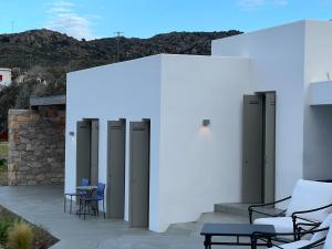 a white building with chairs and tables on a patio at Villa Serene Milos in Empourios