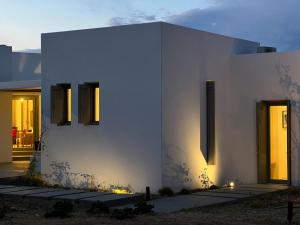 a white house with lights on the side of it at Villa Serene Milos in Empourios