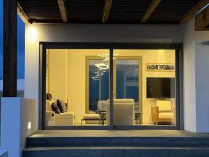 a living room with glass doors and white chairs at Villa Serene Milos in Empourios