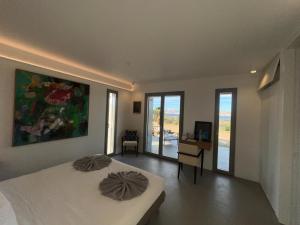 a bedroom with a bed and a desk and windows at Villa Serene Milos in Empourios