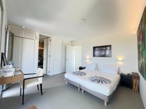 a white bedroom with a bed and a desk at Villa Serene Milos in Empourios