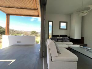 a living room with white furniture and a large window at Villa Serene Milos in Empourios