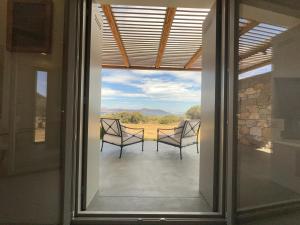 a view from a glass door of a patio with two chairs at Villa Serene Milos in Empourios