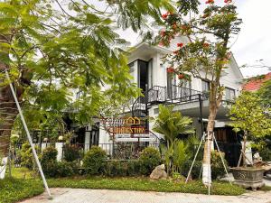 a white house with a sign in front of it at MUN HOMESTAY in Hue