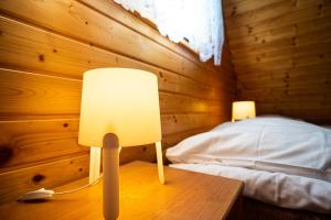 a bedroom with a bed and two lamps on a table at Omega Domki in Gąski