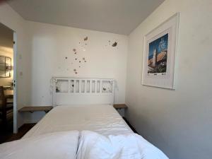 um quarto com uma cama branca e uma fotografia na parede em La Terrasse em Les Sables-dʼOlonne