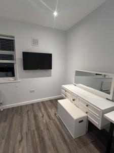 een witte kamer met een bureau en een tv aan de muur bij Spencer bridge Rooms by AFL in Northampton