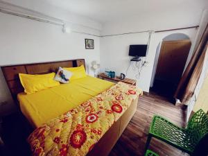 a bedroom with a yellow bed and a chair at The Himalaya Retreat Resort, Experience Nature in the Lap of Himalayas in Mussoorie