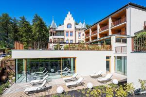 a large white house with chairs on a deck at Villa Waldkönigin in San Valentino alla Muta