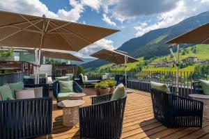 una terraza con sillas, mesas y sombrillas en Adler Resort en Saalbach Hinterglemm