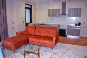 een woonkamer met een bruine bank en een keuken bij KingJada Hotels And Apartments Ltd in Dar es Salaam