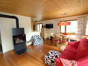 a living room with a red couch and a fireplace at Sunlit Cabin with Jacuzzi in Turracherhohe in Turracher Hohe