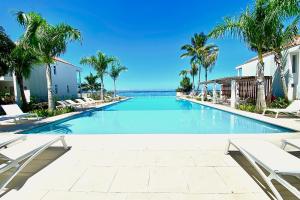 a large swimming pool with chairs and palm trees at GAIA Lodge seaside in Paea