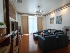a living room with a blue couch and a tv at De Leon Staycation at Vista de Loro in Ternate
