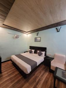 ein Schlafzimmer mit einem großen Bett und einem Stuhl in der Unterkunft Hotel Hidden Chalet Nainital Near Mall Road - Luxury Room - Excellent Customer Service in Nainital