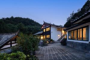 an exterior view of a house with a stone patio at 丽江山之名·音糖·大美华宿（束河古镇店） in Lijiang