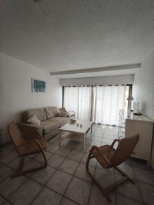 ein Wohnzimmer mit einem Sofa, Stühlen und einem Tisch in der Unterkunft Résidence Palmyra - 2 Pièces pour 4 Personnes 764 in Le Barcarès
