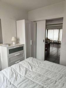 ein Schlafzimmer mit einem weißen Bett und ein Wohnzimmer in der Unterkunft Résidence Palmyra - 2 Pièces pour 4 Personnes 764 in Le Barcarès