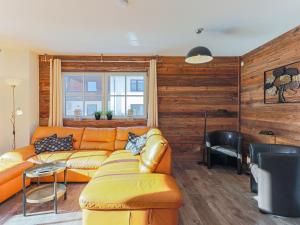 an orange couch in a living room with wooden walls at Modern Apartment near Ski Area in Brixen im Thale in Feuring