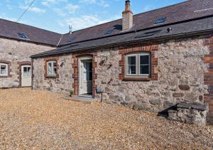 an old stone house with a gravel yard in front of it at The Stables-Cilcain in Cilcain