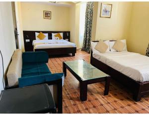 ジャイプールにあるHotel Maziz Prime, Jaipurのベッド、ソファ、テーブルが備わる客室です。