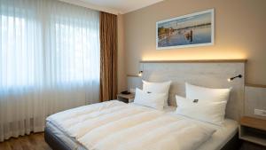 a bedroom with a large bed with white sheets and pillows at Boutique Hotel Rosengarten Hamburg in Hamburg
