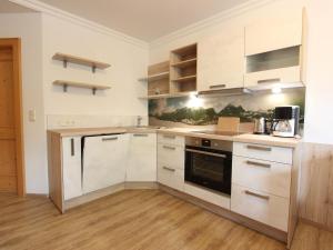 a kitchen with white cabinets and wooden floors at Modern Apartment in Fieberbrunn with Terrace in Fieberbrunn