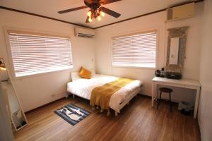 Schlafzimmer mit einem Bett und einem Deckenventilator in der Unterkunft Whale Okinawa in Kadena