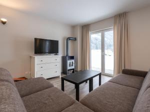 salon z kanapą, telewizorem i stołem w obiekcie Holiday home in ski area in Mittersill w mieście Mittersill