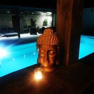 eine Statue eines Kopfes mit einer Kerze vor einem Pool in der Unterkunft Logement cosy avec piscine et jacuzzi privatifs 4 étoiles in Saint-Dolay
