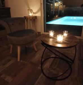ein Wohnzimmer mit einem TV und einem Tisch mit Kerzen in der Unterkunft Logement cosy avec piscine et jacuzzi privatifs 4 étoiles in Saint-Dolay