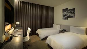 um quarto de hotel com duas camas e uma televisão em Golden Tulip Glory Fine Hotel em Tainan