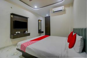 a bedroom with a bed with red pillows and a tv at BHILVA INN in Warangal