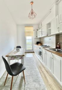 a kitchen with white cabinets and a table and a chair at Urban Sunset Apartment in Sibiu