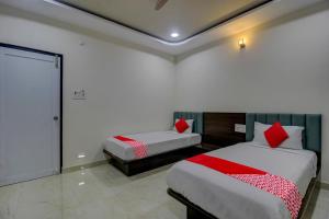 um quarto com 2 camas e almofadas vermelhas em BHILVA INN em Warangal
