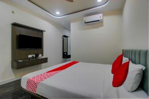 um quarto com uma cama com almofadas vermelhas e uma televisão em BHILVA INN em Warangal