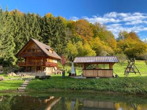 eine große Holzhütte neben einem Fluss mit Bäumen in der Unterkunft Drevenica Starý Mlyn in Prievidza