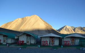a group of tents with red chairs in front of a mountain at Martsemik Camping & Resort Shachukul in Tangtse