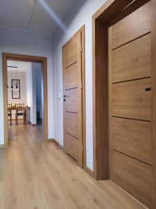 a hallway with two wooden doors and a table at Chabrowa Apartamenty 2 in Milicz