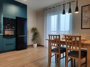 a dining room with a table and chairs and a kitchen at Chabrowa Apartamenty 2 in Milicz