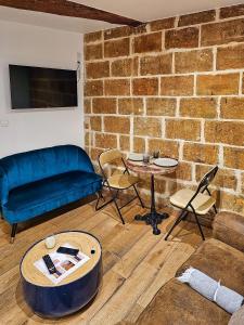 a living room with a couch and a brick wall at Le Chapeau Rouge - Centre Historique - Corum in Montpellier