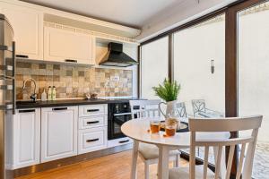 a kitchen with white cabinets and a table and chairs at Ceahlau Cozy House with Terrace, Bbq & Free Parking in Braşov