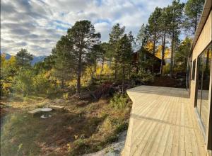 una terraza de madera con un banco en el lateral de una casa en Ny hytte i Malangen, en Nordby