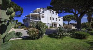 a large white house with trees and plants at Sikelika Residence Sul Mare in Scoglitti