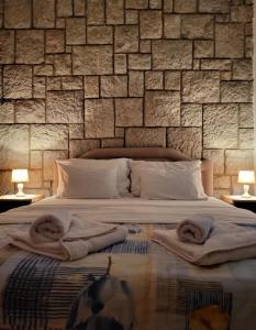 a bedroom with a stone wall with towels on a bed at Apartments Mitrovići Miločer in Sveti Stefan