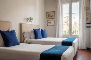two beds in a room with a window at Hotel Medium Romantic in Sitges