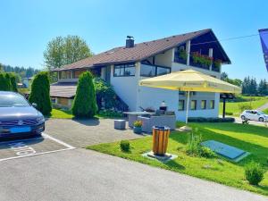 a car parked in front of a house with an umbrella at 16 Lakes Guesthouse in Grabovac